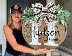 a woman holding up a wooden sign that says the hudson family with flowers on it