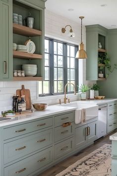 a kitchen with green cabinets and white counter tops, gold faucets and hanging lights