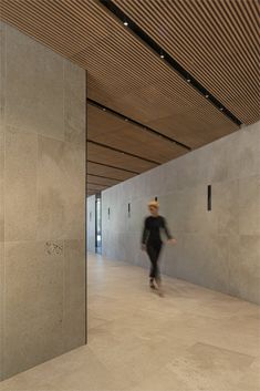 a man in a cowboy hat is walking through an empty room with concrete walls and flooring