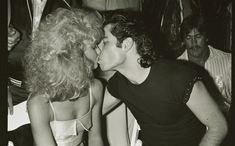 a man kissing a woman on the cheek in front of other people at a party