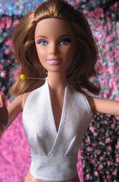 a close up of a doll wearing a white top