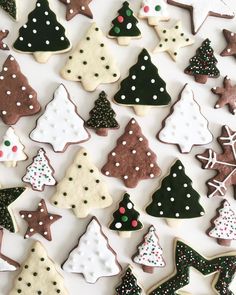 decorated cookies are arranged in rows on a white surface with christmas trees and snowflakes