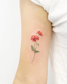 a small red flower tattoo on the right arm