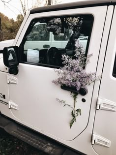 a white jeep with purple flowers in the back window and door handle on it's side