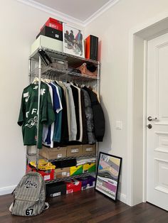 an organized closet with clothes, books and other items on shelves next to a door