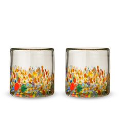 two glasses sitting next to each other on top of a white surface with colorful designs