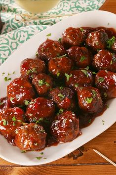 a white plate topped with meatballs covered in sauce and garnished with parsley