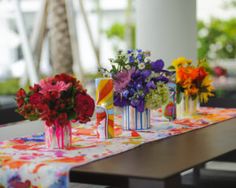 colorful vases with flowers are sitting on a table