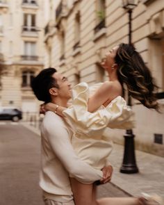 a man carrying a woman on his back down the street in front of a building