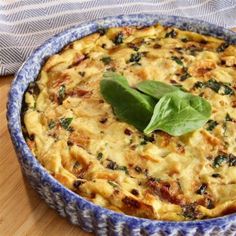 a casserole with spinach and cheese in a blue dish on a wooden table