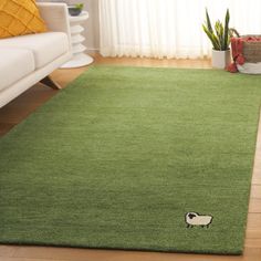 a green rug with a small black and white dog on it in a living room