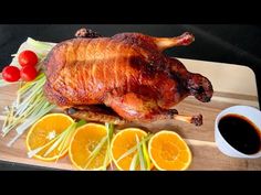 a whole chicken sitting on top of a wooden cutting board next to sliced oranges