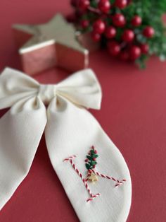 a white tie with a small christmas tree on it's side next to some red berries