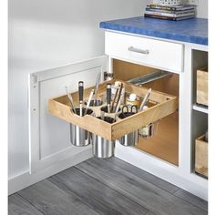 an open drawer in a kitchen filled with utensils and other items on the counter