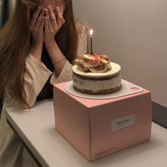 a woman covering her face next to a cake