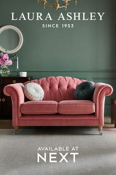 a pink couch in front of a green wall with the name lauren ashley on it