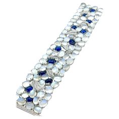 An absolutely stunning bracelet by Sophia D.! There are a total of 77 cabochon cut Moonstones prong set throughout the bracelet and 12 cabochon cut Sapphires, with emerald cut and round brilliant Diamonds. The Moonstones display beautiful adularescence in every stone. The cabochon Sapphires are a rich royal blue color and have a total weight of 20.60 carats, and are off set with handcrafted round brilliant pave Diamond leaves and emerald cut Diamonds. The Diamonds have a total weight of 3.50 car Luxury Silver Bracelets With Cabochon, Cabochon Bracelet, 18k Gold Bracelet, Royal Blue Color, Emerald Cut Diamonds, Moon Stone, Sapphire Diamond, Pave Diamonds, Emerald Cut