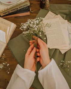 a person arranging flowers on a table with books and other things to do in the background