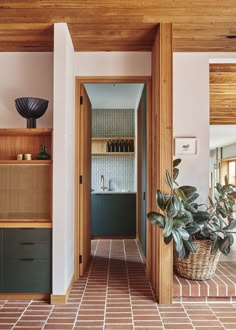 an open kitchen and dining area with tiled flooring, potted plant in the foreground