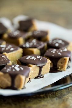 there are many small pieces of food on the plate with white and brown icing