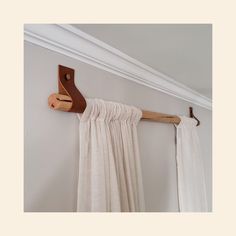 the curtain rod is attached to the wall with a wooden hook on it's side