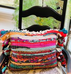 a stack of colorful pillows sitting on top of a chair