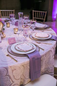 the table is set with purple and white place settings