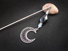 a silver brooch with a black and blue bead hanging from it's side