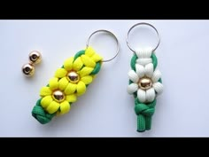 two keychains with flowers on them sitting next to each other, one is yellow and the other is green