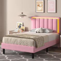 a pink bed with a teddy bear sitting on top of it in front of a wall