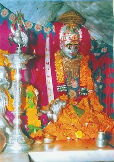 an idol is sitting in front of a silver vase and other items on a table