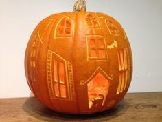 a pumpkin carved to look like a house with windows on the front and side, sitting on a table