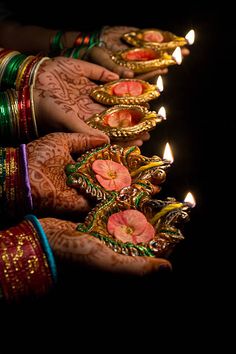 two hands with hendi holding lit candles in front of the words happy diwali