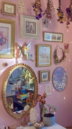 there is a mirror and many pictures on the wall in this room with pink walls