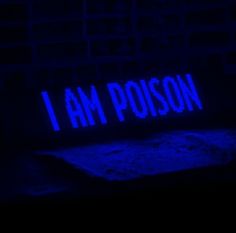 the word i am poison is lit up in blue light on a brick wall