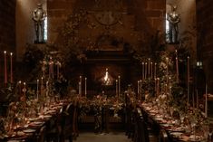 a long dining table is set with candles and flowers in front of a large clock