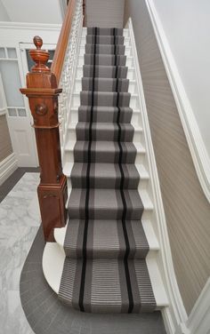 the stairs are lined with black and white striped carpet, along with a wooden handrail