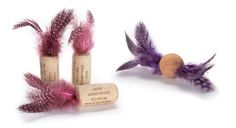 three wine corks with purple feathers on them and a cork stopper in the middle