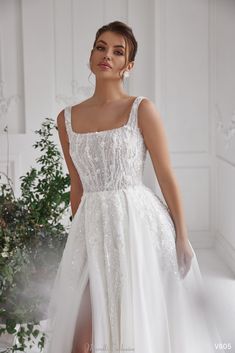 a woman in a white wedding dress standing next to a plant