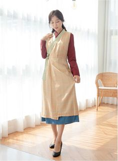 a woman standing in front of a window wearing an apron