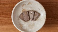 three pieces of leather sitting on top of a white bowl