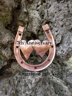 a pair of copper horseshoes sitting on top of a tree trunk with the words 7th anniversary engraved in it