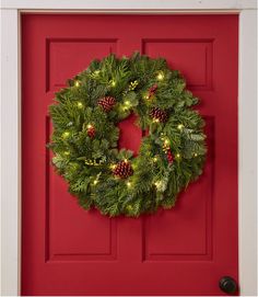 a christmas wreath on a red door with lights