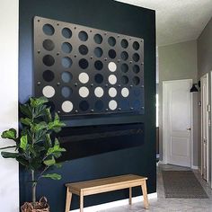 a black wall with white dots on it and a wooden bench in the foreground