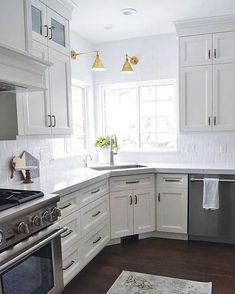 a kitchen with white cabinets and stainless steel appliances in the corner, along with a rug on the floor