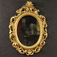 an ornate gold framed mirror hanging on the wall next to a vase with flowers in it