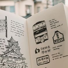 an open book with drawings on it and some buildings in the backgroung