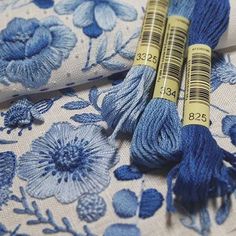 two skeins of yarn sitting on top of a blue flowered table cloth