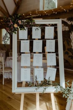 the seating chart was placed on a wooden easel with flowers and greenery around it