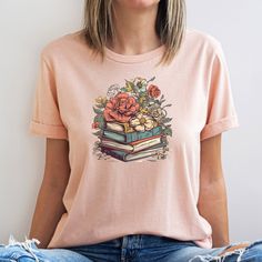 If you or your loved one loves books and flowers, you're a librarian, teacher, or major book lover, this beautiful botanical cottagecore bookish shirt could be just what you've been looking for. With it's whimsical, botanical, book-lover design, you'll love the look and feel of this tee, in fact, it could become your fav. We're loving the design's muted vintage floral tones and hope you'll love them just as much. This design would also make a brilliant Birthday or Mother's Day gift for a loved one. All the technical stuff How to Order: 1. Check our photos for sizing and colour options  2. Choose your size and colour preference from the drop down menus  3. Add to cart & Place order  4. Your shirt is now off to production and will be ready for shipment in 2-5 days!  This t-shirt is everythin Spring Bookish Short Sleeve T-shirt, Bookish Short Sleeve T-shirt For Spring, Spring Bookish Style Short Sleeve T-shirt, Spring Bookish T-shirt With Letter Print, Spring Cotton T-shirt With Bookish Style, Spring Bookish Short Sleeve Tops, Bookish Short Sleeve Tops For Spring, Botanical Cottagecore, Bookish Tshirt